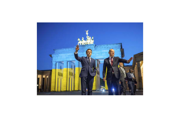 ウクライナ国旗の色に照らされたブランデンブルク門の前で撮影に応じるフランスのマクロン大統領（左）とドイツのショルツ首相＝9日、ベルリン（AP＝共同）