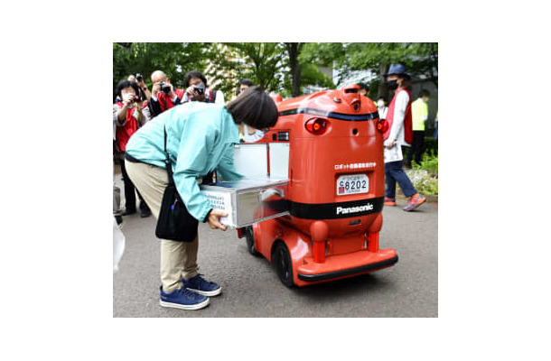商品を積み込まれる自動配送ロボット＝26日、茨城県つくば市