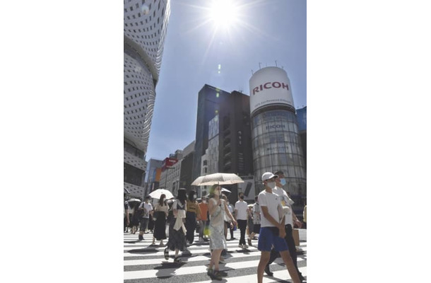 強い日差しが照りつける中、東京・銀座を歩く買い物客ら＝21年7月