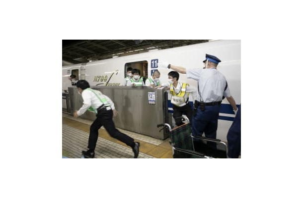 新幹線が本来の位置からずれて停車しながらも、ホームドアを開けて乗客役を避難誘導する駅員＝14日未明、JR新横浜駅