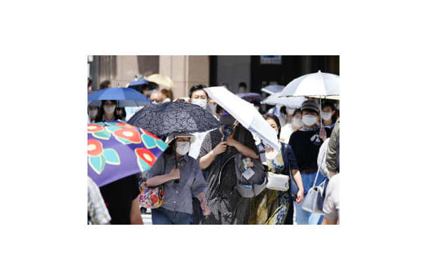 猛烈な暑さの中、日傘を差して歩く人たち＝26日午後、東京・銀座
