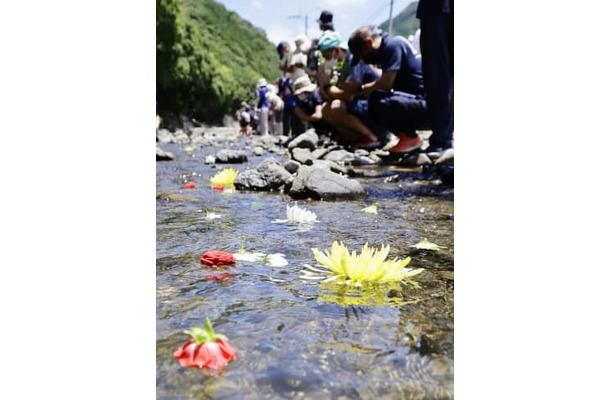 球磨川の支流・川内川に、住民らの手で流された花＝2日午前、熊本県球磨村