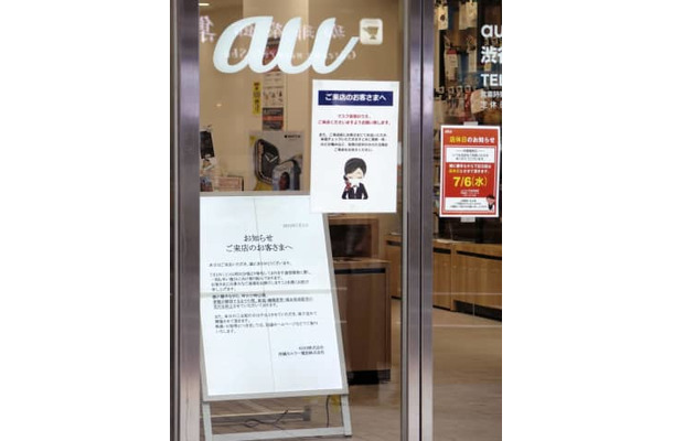 KDDI（au）の大規模通信障害について謝罪の看板を掲げるJR渋谷駅近くのauショップ＝3日午後、東京都渋谷区