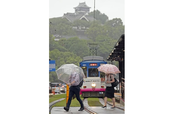 傘を差して熊本市内を歩く人たち。上は熊本城＝5日午前8時11分