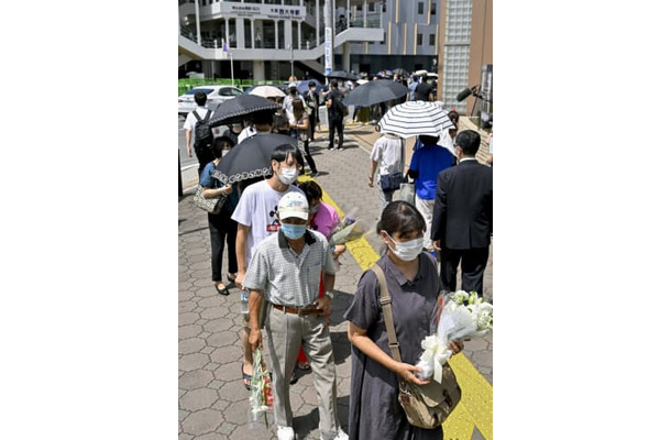 安倍元首相が銃撃された現場付近に設置された献花台に並ぶ人たち＝9日午前10時36分、奈良市