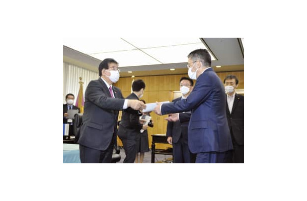 KDDIの高橋誠社長（手前右）に行政指導の文書を渡す金子総務相＝3日午後、総務省
