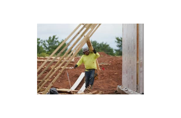 住宅建設現場で板を運ぶ作業員＝2021年6月、米オクラホマ州（AP＝共同）
