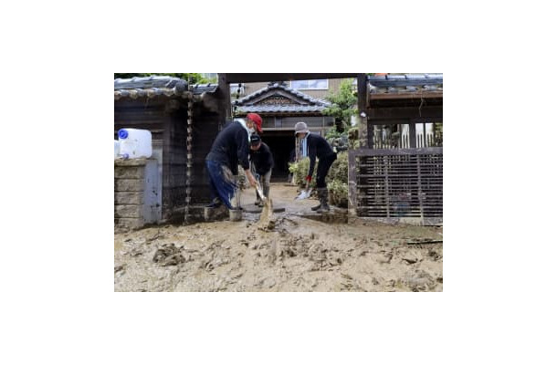 ボランティアと泥をかき出す男性（左）＝8日、福井県南越前町