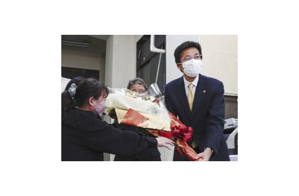 当選が決まり、事務所で花束を受け取る斉藤栄氏（右）＝11日夜、静岡県熱海市