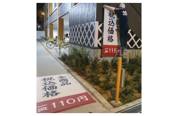 価格が表示された垂れ幕を交換するくら寿司朝潮橋店の従業員＝9月30日夜、大阪市港区