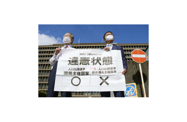 参院選の「1票の格差」訴訟の判決を受け、大阪高裁前で「違憲状態」と書かれた紙を掲げる原告側の升永英俊弁護士（左）ら＝14日午後