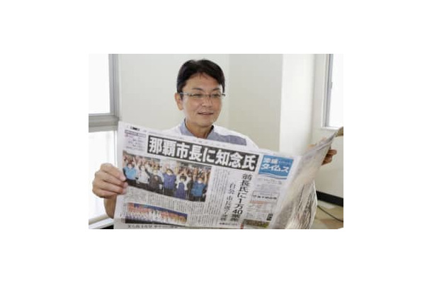 那覇市長選から一夜明け、初当選を報じる新聞を手にする知念覚氏＝24日午前、那覇市