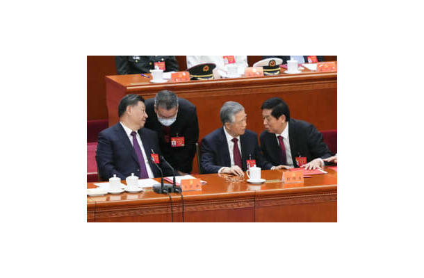 第20回中国共産党大会の閉幕式で、胡錦濤前総書記（右から2人目）の書類を手で押さえる栗戦書氏。左端は習近平総書記＝22日、北京の人民大会堂（共同）