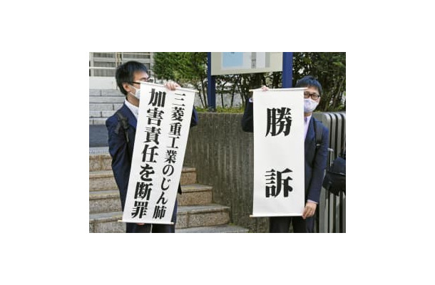 判決後に「勝訴」などと書かれた垂れ幕を掲げる原告側弁護士＝7日午前、長崎地裁前