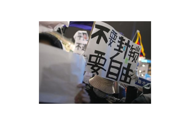 JR新宿駅周辺でメッセージを掲げ、中国共産党の独裁的な統治に抗議する在日中国人ら＝30日夜、東京都新宿区