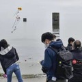 事故の追悼式で、砂浜から海へ献花する参加者＝12日午後、山口県宇部市