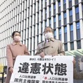 福岡高裁前で「違憲状態」と書かれた紙を掲げる原告側の升永英俊弁護士（右）ら＝21日午後