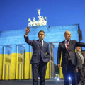 ウクライナ国旗の色に照らされたブランデンブルク門の前で撮影に応じるフランスのマクロン大統領（左）とドイツのショルツ首相＝9日、ベルリン（AP＝共同）