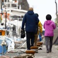 事故の現場海域周辺に行く船に向かう地元の小型観光船の運航関係者ら。花束を手にしていた＝23日午前、北海道斜里町