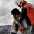 沖縄・波照間島沖で海上保安庁に救助される女性（左）＝14日午前（第11管区海上保安本部提供）