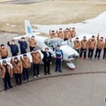 軽量飛行機を囲んで記念撮影するテクノアカデミーの学生と室屋義秀選手